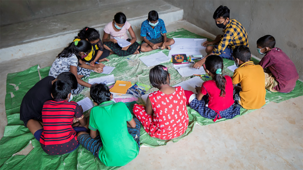 Lapset istuvat lattialla koulussa Odishan syrjäisillä kylillä.