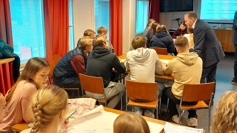 Ministeri Poutala keskustelee nuorten kanssa luokkahuoneessa.