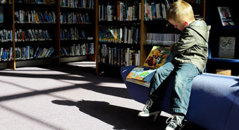Poika lukee kirjastossa
