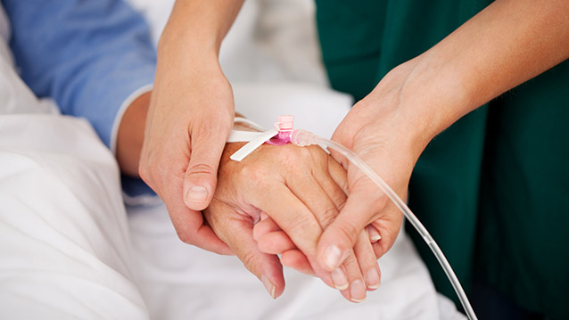 Sairaanhoitaja pitää potilasta kädestä