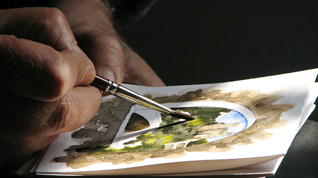 Taiteilijan käsi, joka maalaa akvarellia.